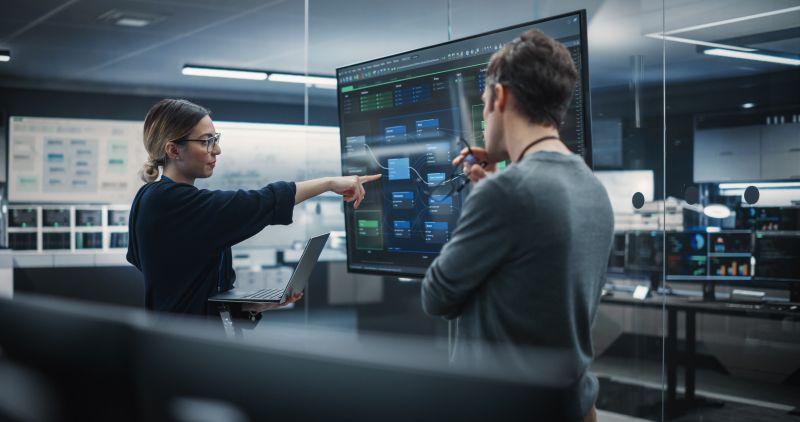 Business France - Two Diverse Software Developers Having a Meeting in a Conference Room. Female and Male Tech Industry Engineers Brainstorming Ideas for Their Neural Network Blockchain Startup